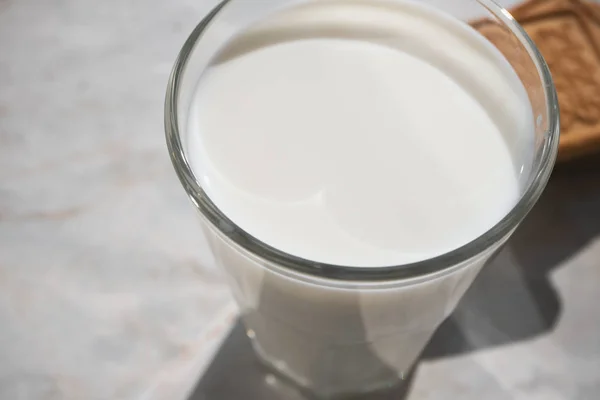 Närbild på mjölk ytan i glas och shortbread på bakgrunden — Stockfoto