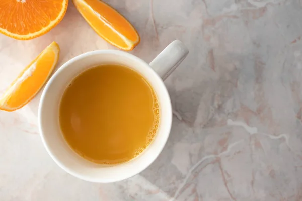 Primer plano de la taza de jugo de naranja casero fresco y naranjas cortadas o — Foto de Stock