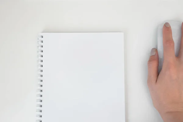 Cuaderno espiral de papel blanco vacío y mano femenina en el ordenador mo — Foto de Stock