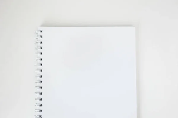 Cuaderno de papel blanco vacío con espiral sobre escritorio blanco, vista superior . — Foto de Stock