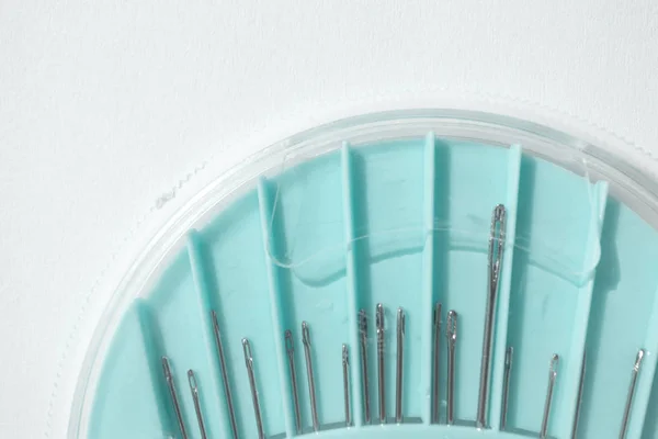 Set of hand-sewing needles in blue round plastic box, close-up. — Stock Photo, Image