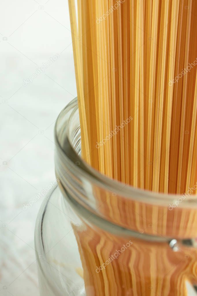 Long spaghetti in glass jar. Ingredient for Italian pasta. Raw f