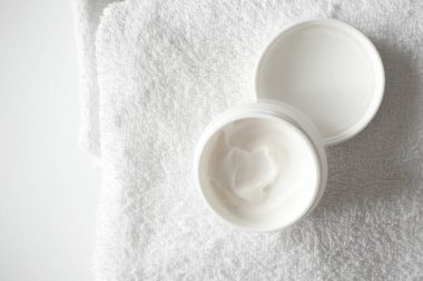 Beyaz banyo havlusuna nemlendirici krem ya da vücut losyonu sür ve boşluğu kopyala. Güzellik tedavi ürünleri, yukarıda.