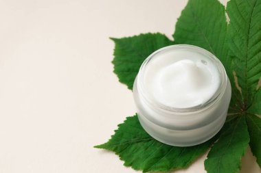 Nemlendirici krem ya da bej arka planda at kestanesi yaprağı üzerinde vücut losyonu. Cilt bakım ürünü, yakın plan.