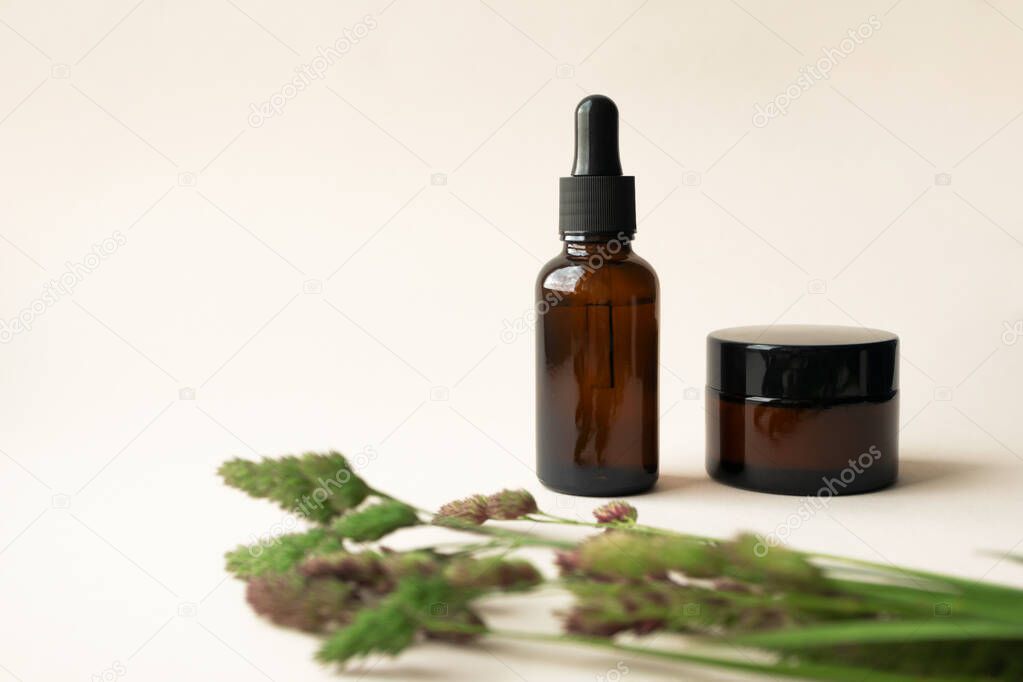 Aromatherapy oil and massage cream or balm in brown glass bottle and jar on light beige background with copy space on left. Concept eco organic natural cosmetic products for skincare