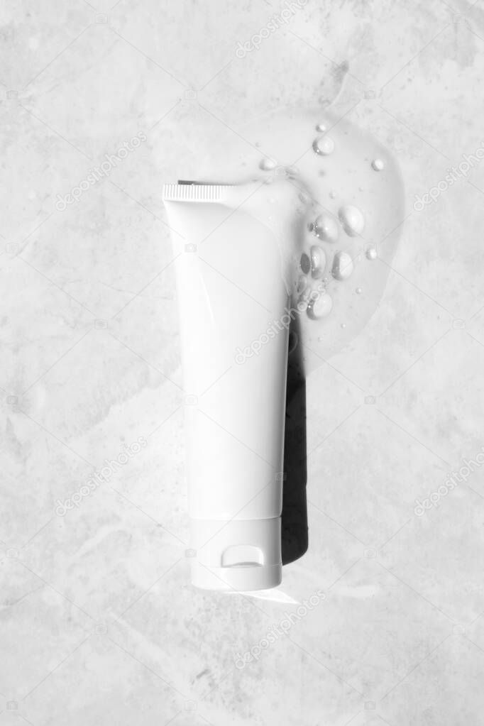 White plastic tube mockup with moisturizer cream, shampoo or facial cleanser and gentle soap foam with bubbles on marble background, top view. Treatment spa beauty skincare cosmetic product