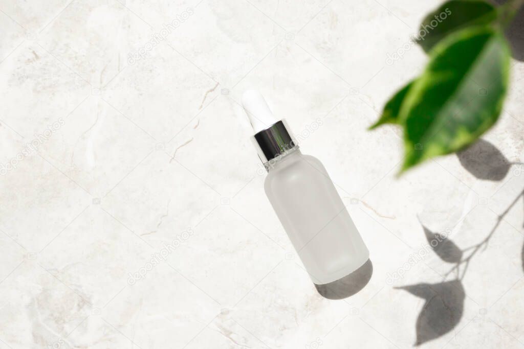 Serum with vitamin E and collagen in frost glass bottle on marble background. Concept of natural cosmetic with copy space at left