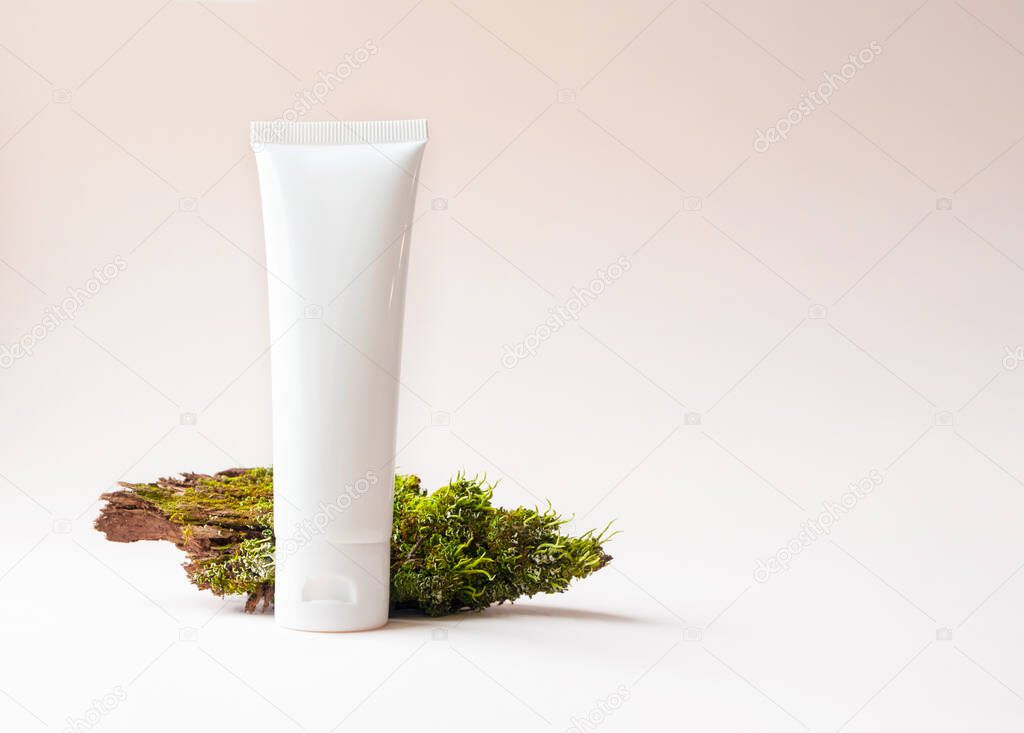Mockup white plastic tube with facial or hand moisturizer cream or facial cleanser and tree bark with moss on beige background with copy space. Concept bio organic beauty products with natural extract