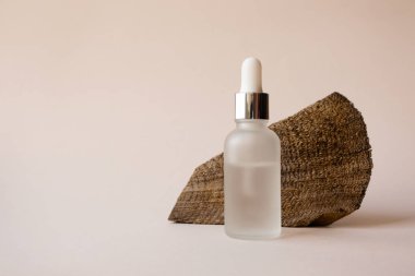 Yüz hiyalüronik nemlendirici şeffaf serum sıvısı pipette ve desenli odağından çıkarılmış ağaç kesimi bej arka planda. Çevresel doğal güzellik cilt modelleme ürünü
