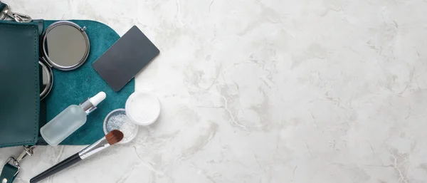Kompakt cep aynası, yüz serumu, şeffaf toz ve kredi kartı mermer masanın üzerinde düz bir şekilde duruyor. Güzellik ve moda blogu için yatay afiş biçimi. Alışveriş.