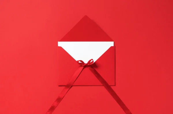 赤い背景に弓サテンリボンと赤い封筒でモックアップ空の手紙紙 グリーティングカード はがき 平らな祝日お祝い — ストック写真