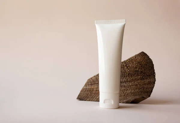 Beyaz güzel cilt ürünü tüp ve bej arka planda odağını kaybetmiş tahta kesim yüzey. Markalaşmak için organik doğal kozmetik modelleme