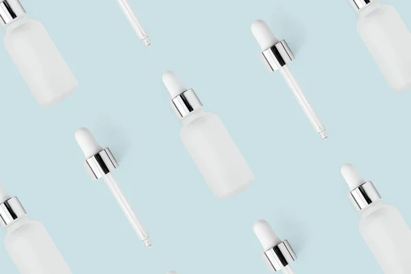 Şişelerde yüz serumu nemlendiricisi ve açık mavi minimalist pastel arka planda cam pipet deseni. Cilt bakım ürünü için model, üst görünüm. Tekrarlanan güzellik duvar kağıdı