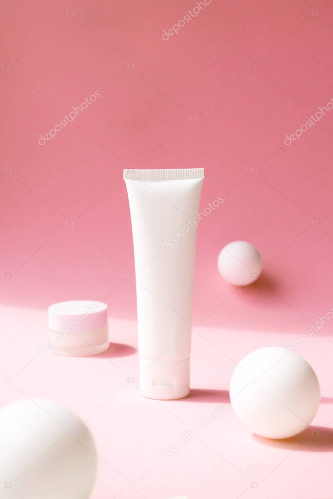 Set for facial skincare care on pink background with abstract white spheres and copy space, vertical. Containers for eye moisturizer, cream, lotion, cleanser, shampoo. Mockup cosmetic product