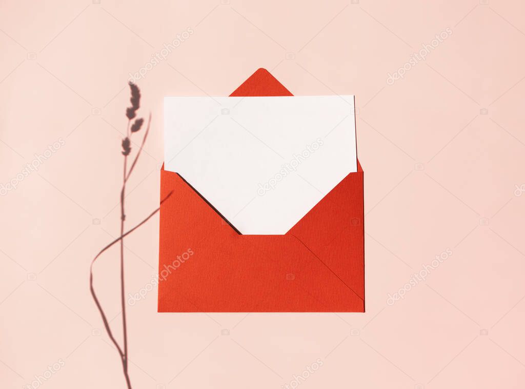Mockup blank letter or postcard in red envelope and shadow at meadow herb on beige background. Creative flat lay composition, above. Summer, autumn greeting card concept