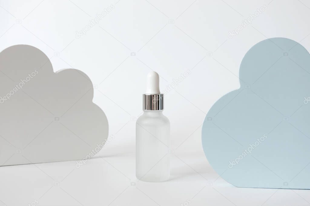 Hydrating moisture mist glass bottle with dropper, cloud shape decor on white background. Minimalist composition beauty product presentation. Concept delicate skin care