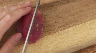 Cutting prickly pear cactus fruit opuntia on wooden board. Ficus indica close-up