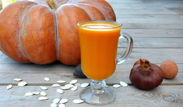 Pumpkin juice in a glass for a weight loss program. Autumn vitamin still life on a wooden background.