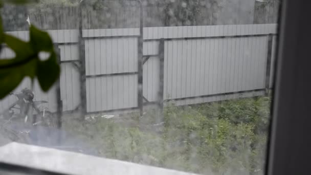 Regen. Buiten het raam is er een zware regenbui. Er lopen druppels water door het glas. Sterke wind en regenachtig weer buiten. Video met geluid. — Stockvideo