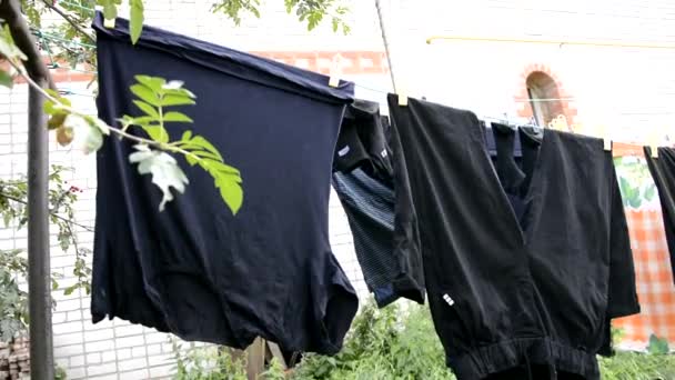 Prádelna je vysušená na laně. Mokrá prádelna visící na lanech na čerstvém vzduchu na slunci. Vyprané šaty visí na ulici poblíž domu, aby uschly.. — Stock video