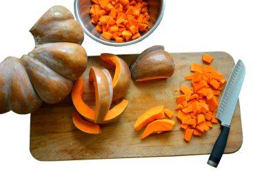 Kesme tahtasının üzerinde dilimlenmiş büyük olgun bir balkabağı yatıyor. İzole edilmiş.