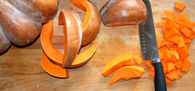 Kesme tahtasının üzerinde dilimlenmiş olgun balkabağı yatıyor..