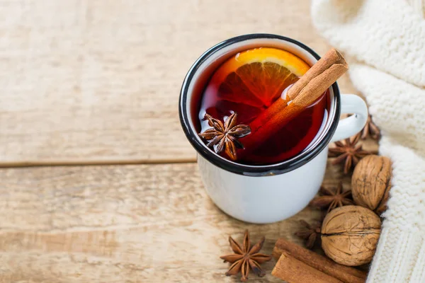 Traditional mulled wine in mug with spice on wooden background