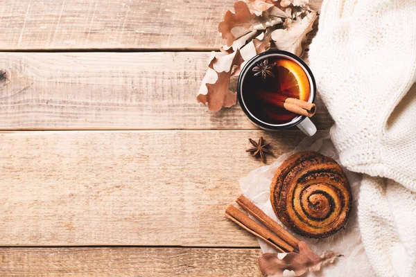 Traditional mulled wine in mug with pastry and spice on wooden background
