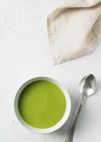 Green vegetable soup on white background minimalism, copy space, top view, vertical