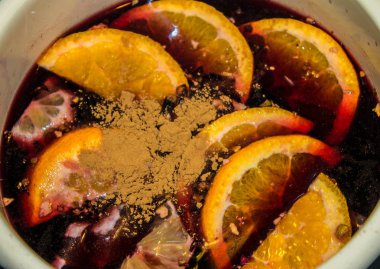 Mulled şarap bir tencerede pişirilir. Portakal ve tarçın ile mulled şarap.