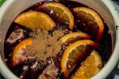 Mulled şarap bir tencerede pişirilir. Portakal ve tarçın ile mulled şarap.