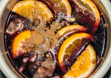 Mulled şarap bir tencerede pişirilir. Portakal ve tarçın ile mulled şarap.