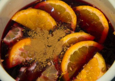 Mulled şarap bir tencerede pişirilir. Portakal ve tarçın ile mulled şarap.
