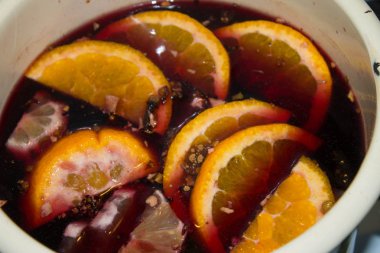 Mulled şarap bir tencerede pişirilir. Portakal ve tarçın ile mulled şarap.