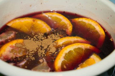 Mulled şarap bir tencerede pişirilir. Portakal ve tarçın ile mulled şarap.