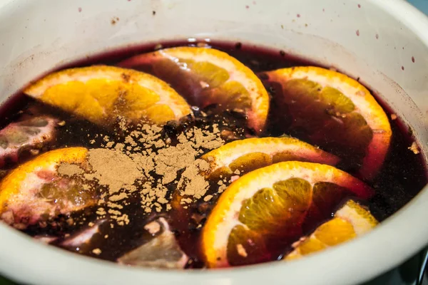 Mulled şarap bir tencerede pişirilir. Portakal ve tarçın ile mulled şarap.