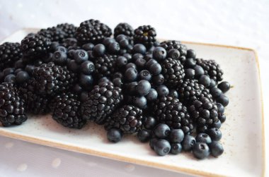 Seramik bir kırsal tabakta yabanmersini ve böğürtlen karışımı.