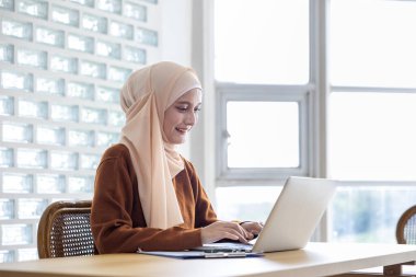 Ortadoğu Müslüman öğrencisi üniversitede ticaret ve dinle ilgili araştırmalar ve eğitim eğitimi için dizüstü bilgisayar kullanarak okulda oturuyor