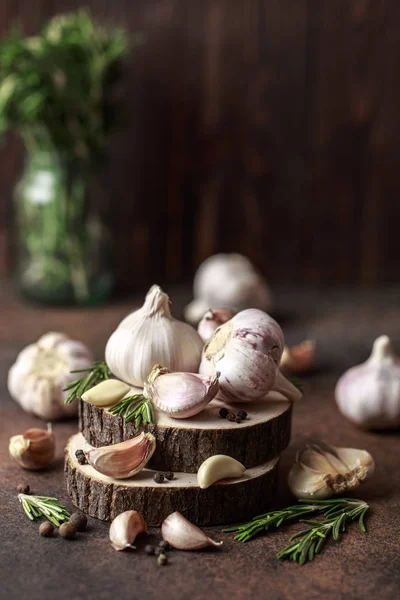 Garlic bulbs with cloves and rosemary on sawed wood on brown background — Stock Image Garlic Bulbs Cloves Rosemary Sawed Wood Brown Background Royalty Free Stock Images