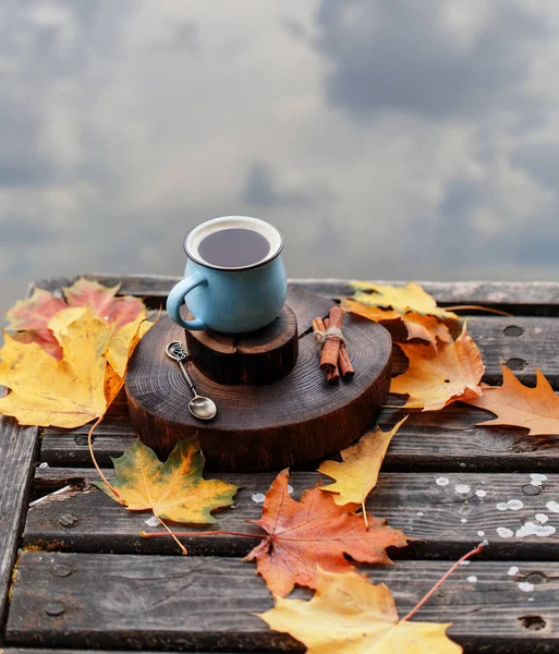 cup of coffee on wooden table with golden foliage