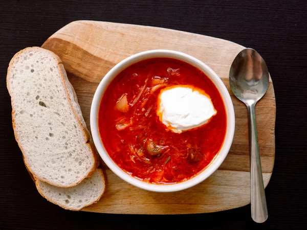 Koyu arkaplanda beyaz ekmek olan Ukrayna kırmızı borsch 'u. Geleneksel Rus mutfağı. Üst görünüm, düz uzanma