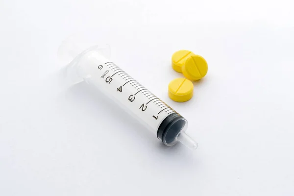 在白色背景下分离的注射器和药丸 — 图库照片