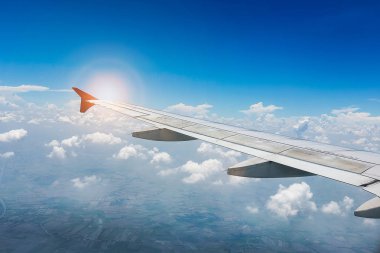 Uçağın kanadı mavi gökyüzünde güneş ışığıyla birlikte. seyahat kavramı
