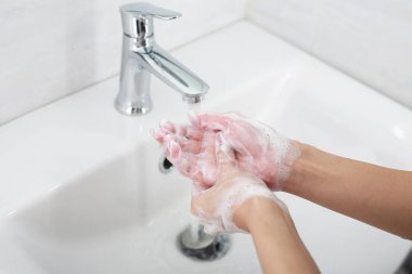 Musluğun altında sabunla ellerini yıkamak, suyla..