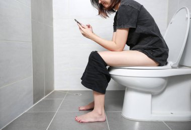 Kadın akıllı telefonu alıp tuvalette mutluluk smile.