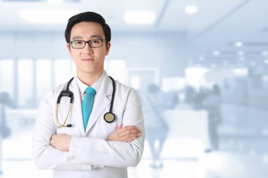 Silah ile poz Doktor geçti, bulanık arka planda çalışan tıbbi personel.