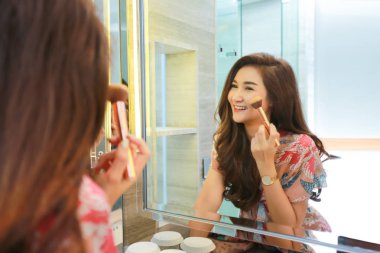 Kadın makyaj için hazırlanıyor, banyoya koyuyor. 