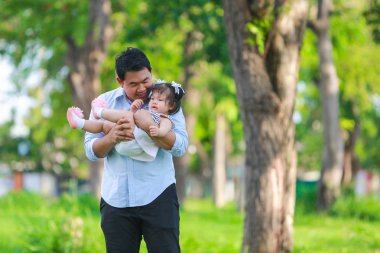 Baba ve kızı oynarken ve parkta koşuşturuyor.