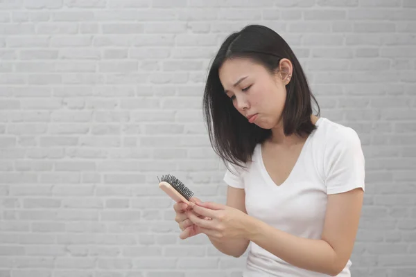 Girl with a comb and problem hair loss on background. — Stock Photo, Image