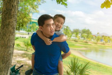 Oğlu parkta komik geri babalar üzerine tırmanıyor.
